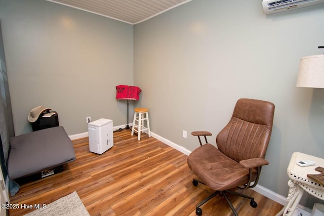 living area with a wall mounted air conditioner and light hardwood / wood-style floors