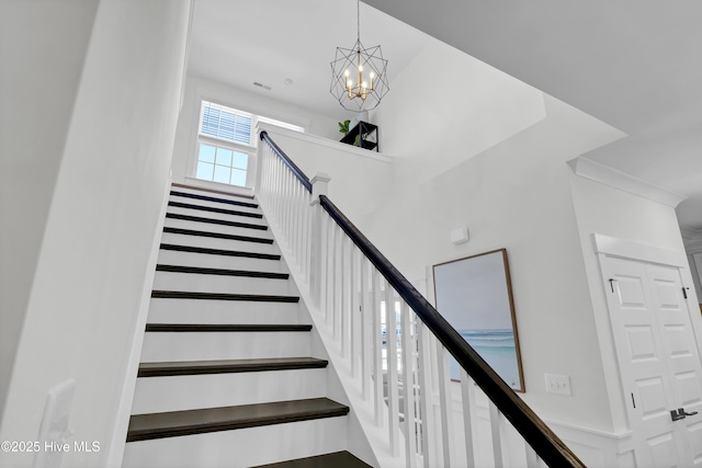 staircase with a notable chandelier