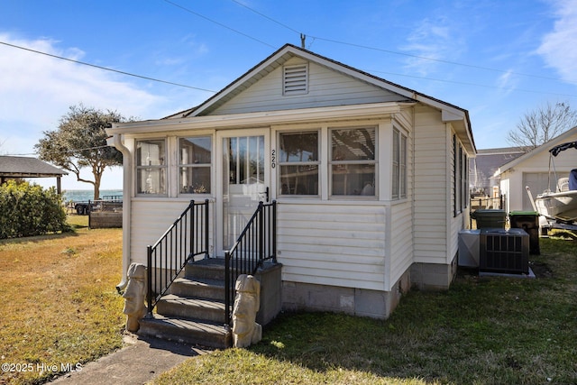 bungalow-style house featuring a front yard and cooling unit