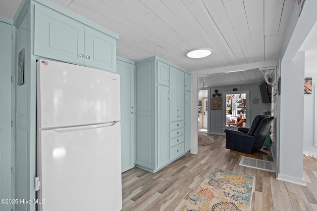 kitchen featuring wood ceiling, wooden walls, white refrigerator, and light hardwood / wood-style flooring