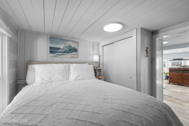 bedroom featuring light wood-type flooring, wooden walls, and wooden ceiling