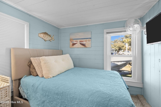 bedroom with wooden walls and multiple windows