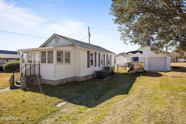 exterior space featuring a garage, central AC, a lawn, and an outdoor structure