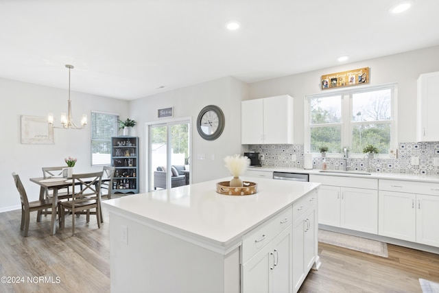 kitchen with decorative backsplash, a kitchen island, sink, white cabinetry, and hanging light fixtures