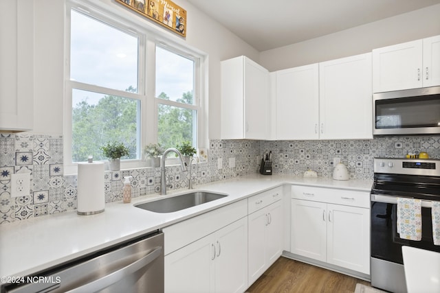 kitchen with backsplash, sink, white cabinets, and appliances with stainless steel finishes