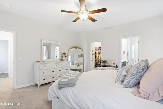 bedroom with light colored carpet, ceiling fan, a spacious closet, connected bathroom, and a closet