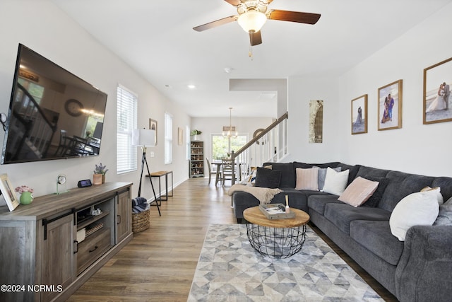 living room featuring ceiling fan with notable chandelier and light hardwood / wood-style flooring