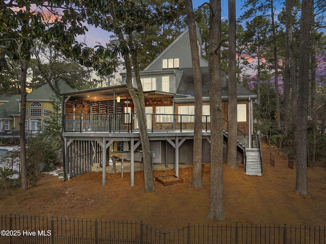 back house at dusk featuring a wooden deck