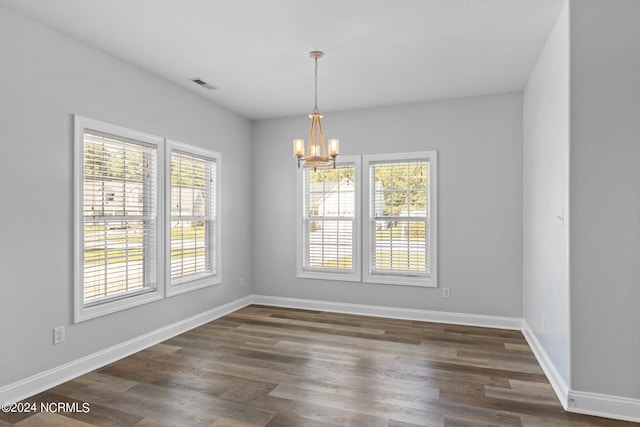 unfurnished dining area featuring dark wood-type flooring and a notable chandelier