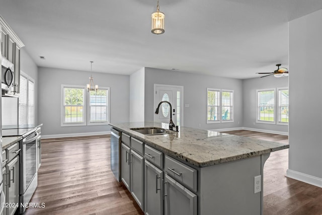 kitchen with appliances with stainless steel finishes, sink, gray cabinets, hanging light fixtures, and an island with sink