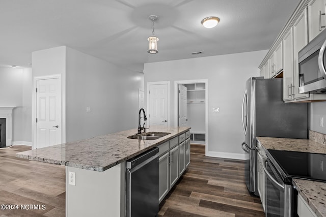 kitchen with sink, hanging light fixtures, dark hardwood / wood-style floors, a kitchen island with sink, and appliances with stainless steel finishes