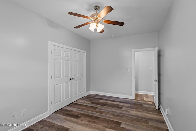 unfurnished bedroom with ceiling fan, a closet, and dark wood-type flooring