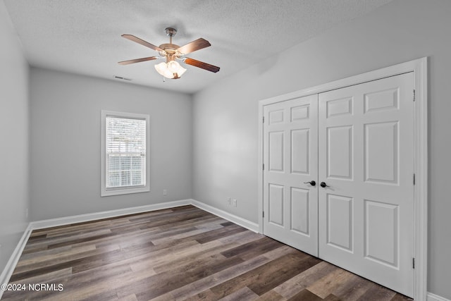 unfurnished bedroom featuring ceiling fan, dark hardwood / wood-style floors, a textured ceiling, and a closet