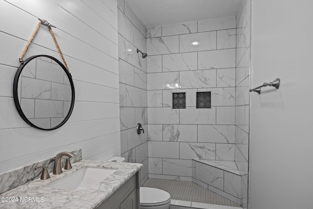 bathroom with vanity, toilet, tiled shower, and wooden walls