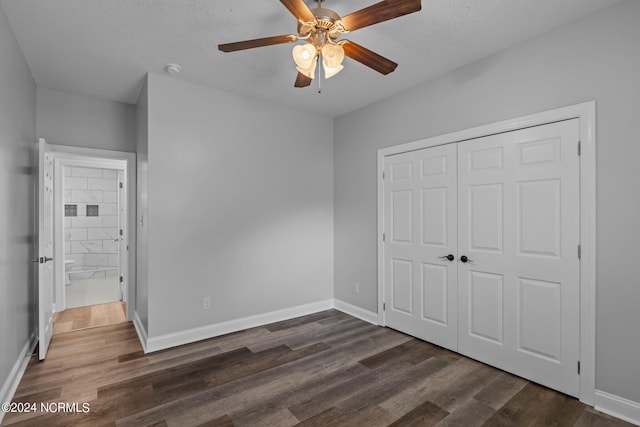 unfurnished bedroom with ceiling fan, a closet, dark wood-type flooring, and a textured ceiling