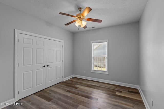 unfurnished bedroom featuring a textured ceiling, a closet, ceiling fan, and dark hardwood / wood-style floors