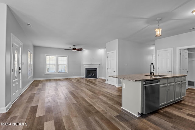 kitchen with light stone countertops, a kitchen island with sink, sink, gray cabinets, and hanging light fixtures