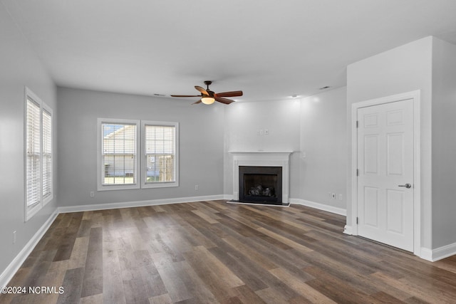 unfurnished living room with dark hardwood / wood-style flooring and ceiling fan