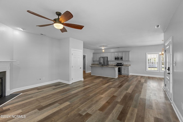 unfurnished living room with dark hardwood / wood-style flooring and ceiling fan