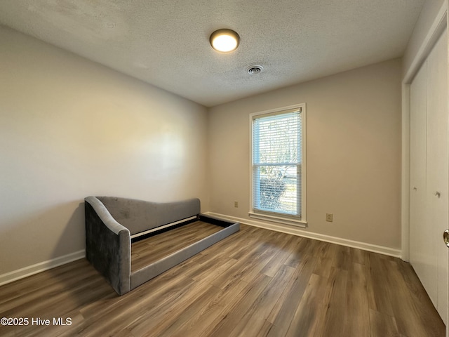 unfurnished bedroom with a textured ceiling, hardwood / wood-style flooring, and a closet