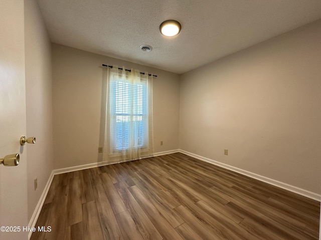 unfurnished room with a textured ceiling and dark hardwood / wood-style floors