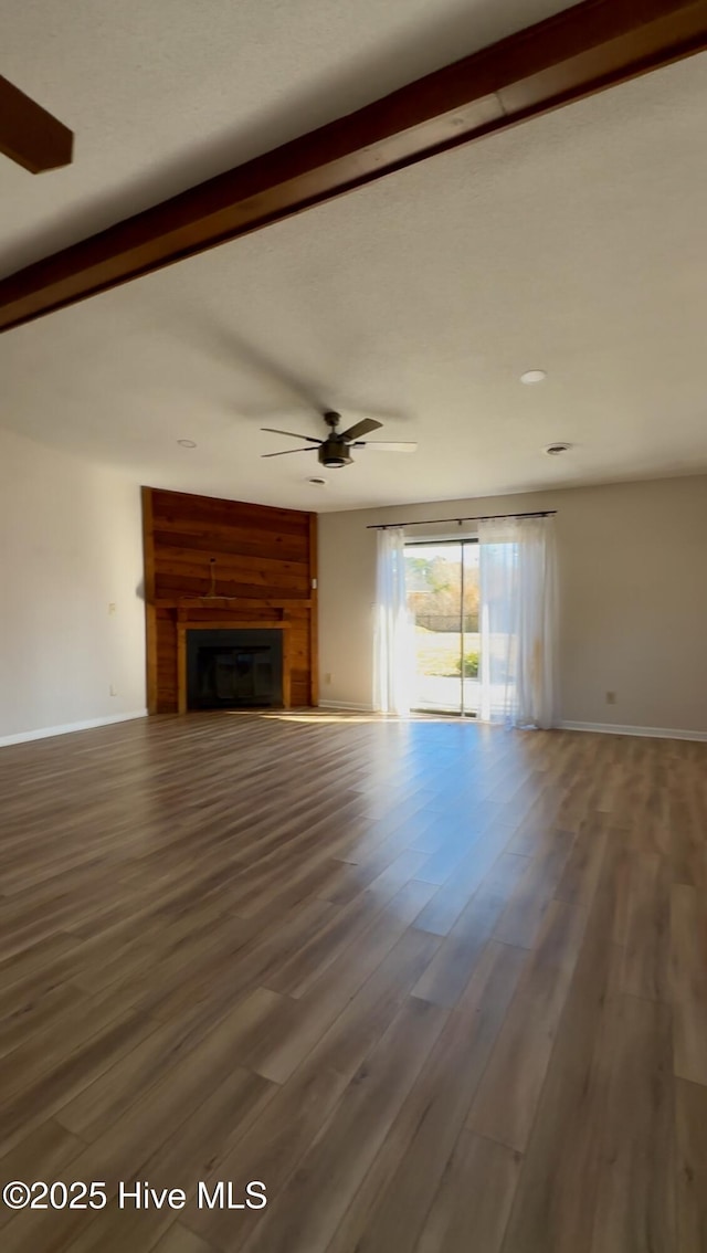 unfurnished living room with beam ceiling, ceiling fan, and wood-type flooring