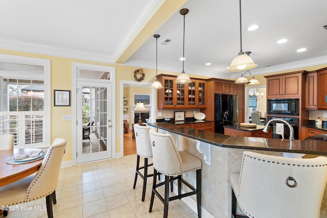 kitchen with a kitchen island, crown molding, visible vents, and black appliances