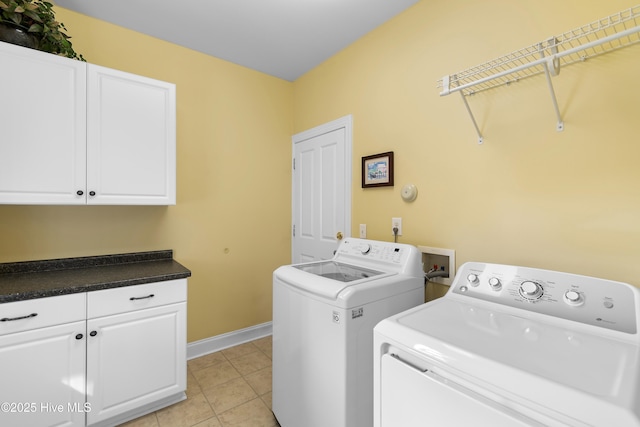 clothes washing area with baseboards, cabinet space, light tile patterned floors, and washing machine and clothes dryer