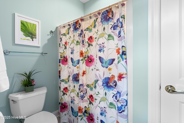 bathroom featuring toilet and curtained shower