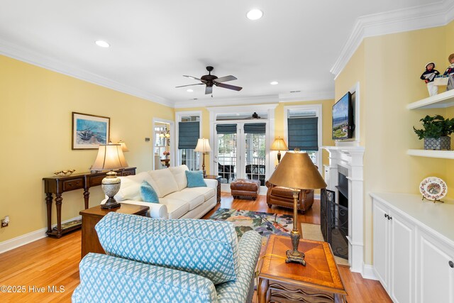 living room with crown molding, ceiling fan, built in shelves, and light hardwood / wood-style floors