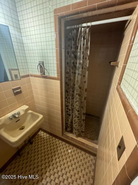 bathroom with tile walls, a shower with curtain, and tile patterned floors