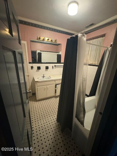 bathroom with shower / bathtub combination with curtain, vanity, tasteful backsplash, and ornamental molding