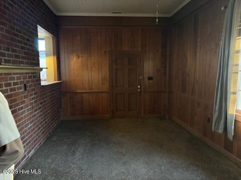 carpeted spare room with brick wall and wooden walls