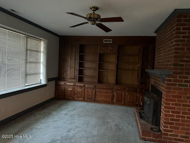 unfurnished living room featuring a fireplace, ornamental molding, ceiling fan, and carpet