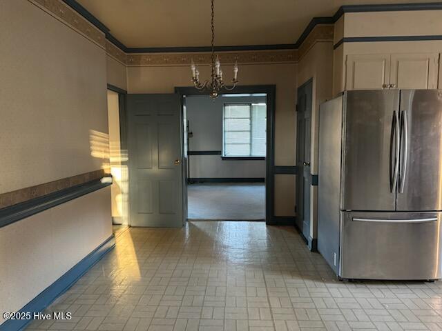 kitchen with crown molding, decorative light fixtures, stainless steel fridge, a notable chandelier, and white cabinets