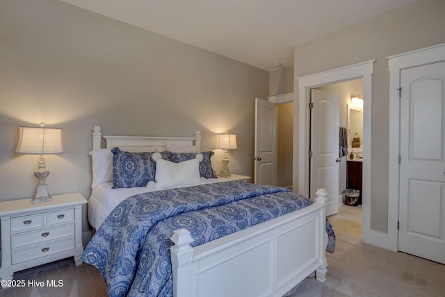 bedroom featuring ensuite bathroom and light colored carpet