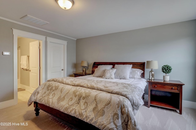 carpeted bedroom with ensuite bathroom and ornamental molding