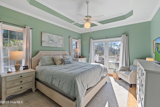 bedroom featuring ceiling fan, access to outside, a tray ceiling, light wood-type flooring, and crown molding