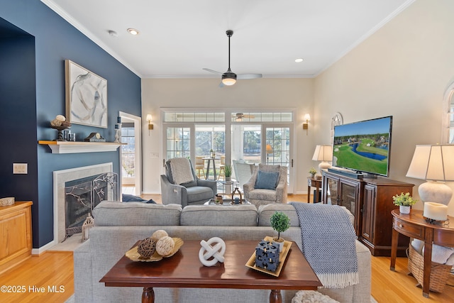 living room with ceiling fan, ornamental molding, and light wood-type flooring