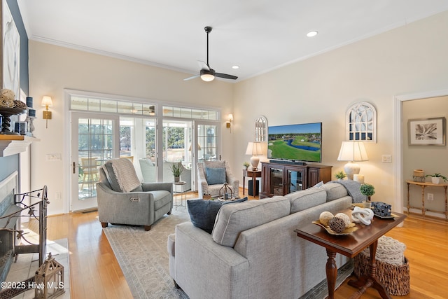 living room with ceiling fan, ornamental molding, and light hardwood / wood-style flooring