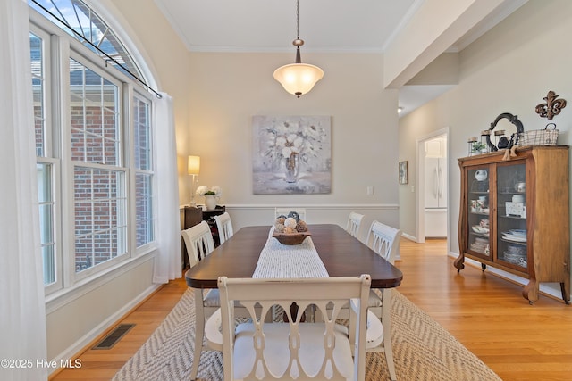 dining room with light wood-type flooring and crown molding