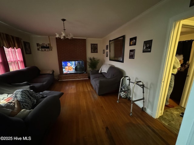 living room featuring ornamental molding, hardwood / wood-style floors, a chandelier, and a brick fireplace