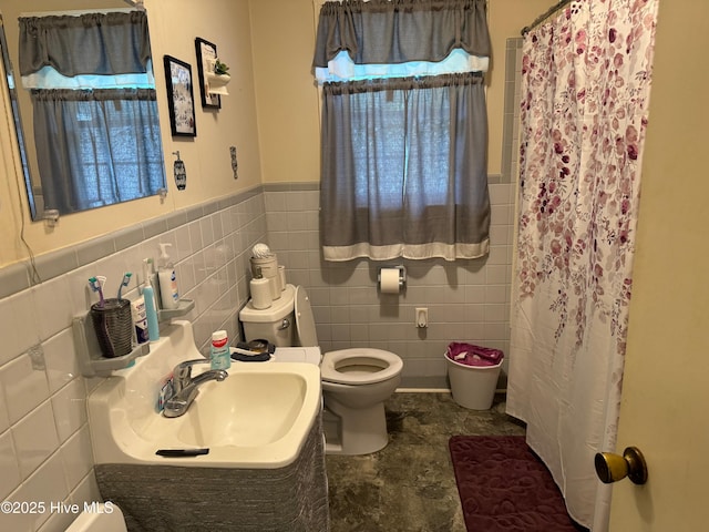 bathroom with curtained shower, toilet, sink, and tile walls