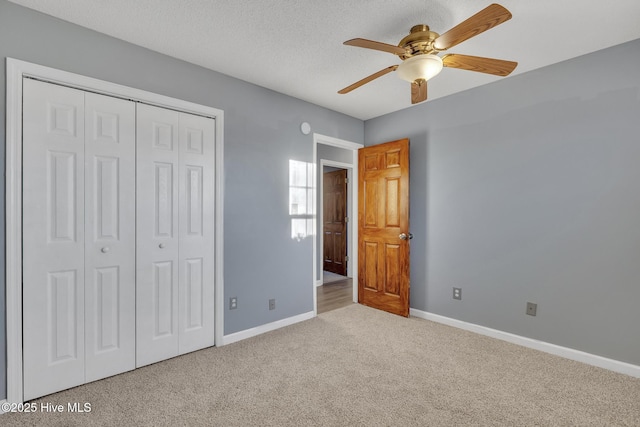 unfurnished bedroom with a textured ceiling, ceiling fan, a closet, and light colored carpet