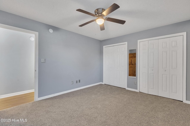 unfurnished bedroom featuring ceiling fan, multiple closets, a textured ceiling, and carpet flooring