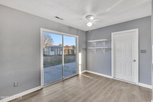 empty room with ceiling fan, a textured ceiling, and light hardwood / wood-style flooring