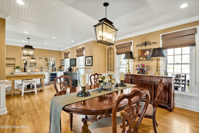 dining room featuring a notable chandelier, beverage cooler, light hardwood / wood-style floors, and ornamental molding