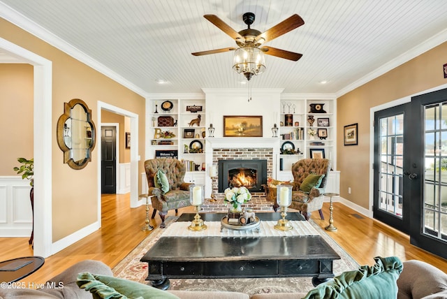 living room with light hardwood / wood-style floors, french doors, ornamental molding, and built in shelves