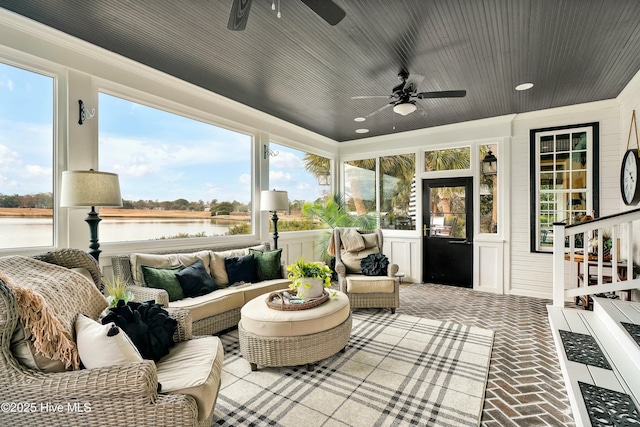 sunroom with ceiling fan, a water view, and plenty of natural light