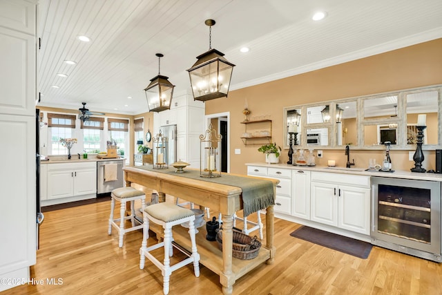 kitchen featuring white cabinets, beverage cooler, appliances with stainless steel finishes, and hanging light fixtures